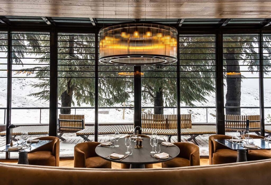 Maribel restaurant in Sierra Nevada, featuring an elegant dining space with plush seating, ambient lighting, and floor-to-ceiling windows overlooking a snowy alpine landscape. A refined mountain retreat for gourmet experiences.
