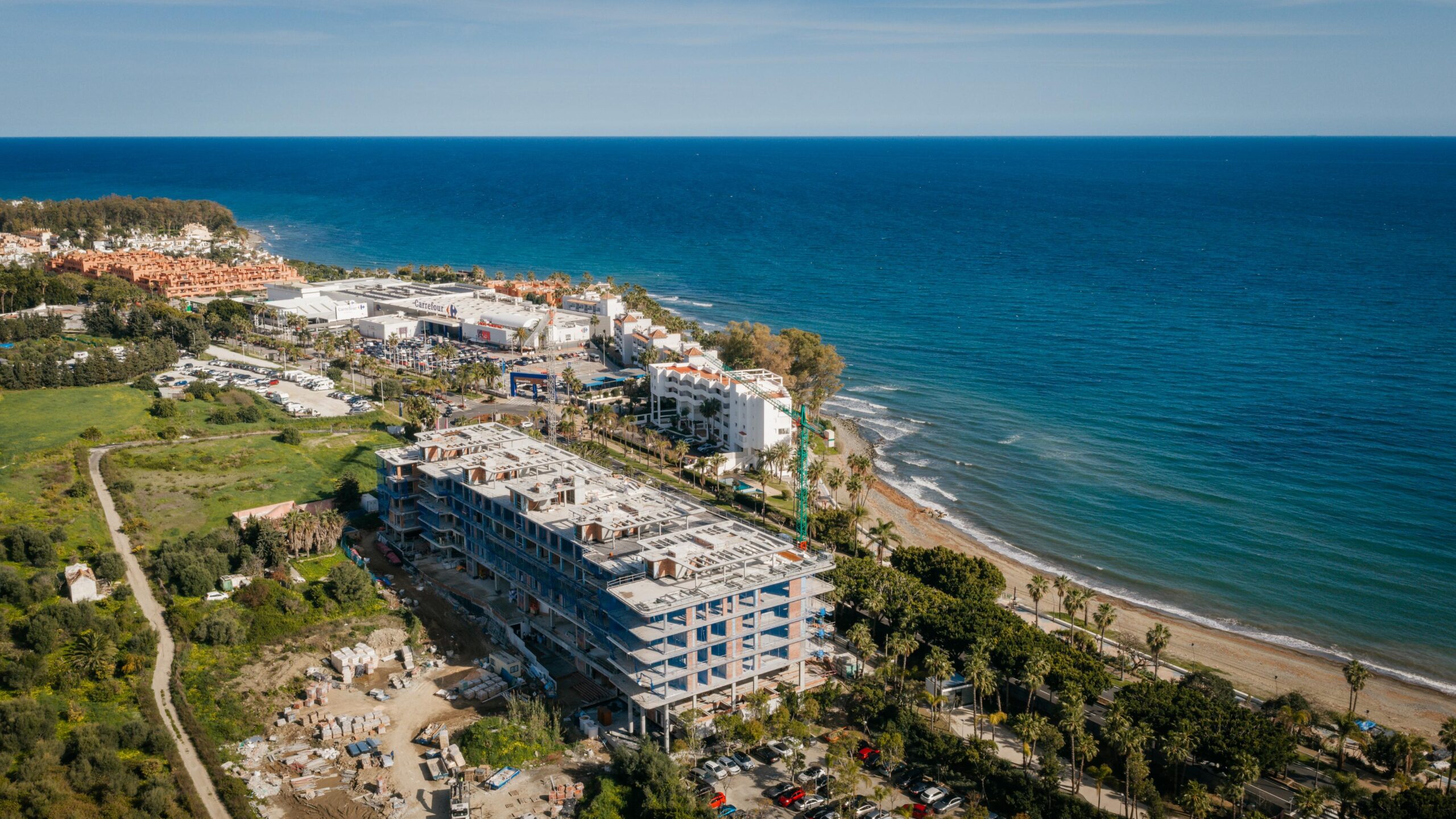 Aerial view of Tyrian Residences under construction on Playa de la Rada, Estepona, beachfront position with the coastline extending toward Marbella.